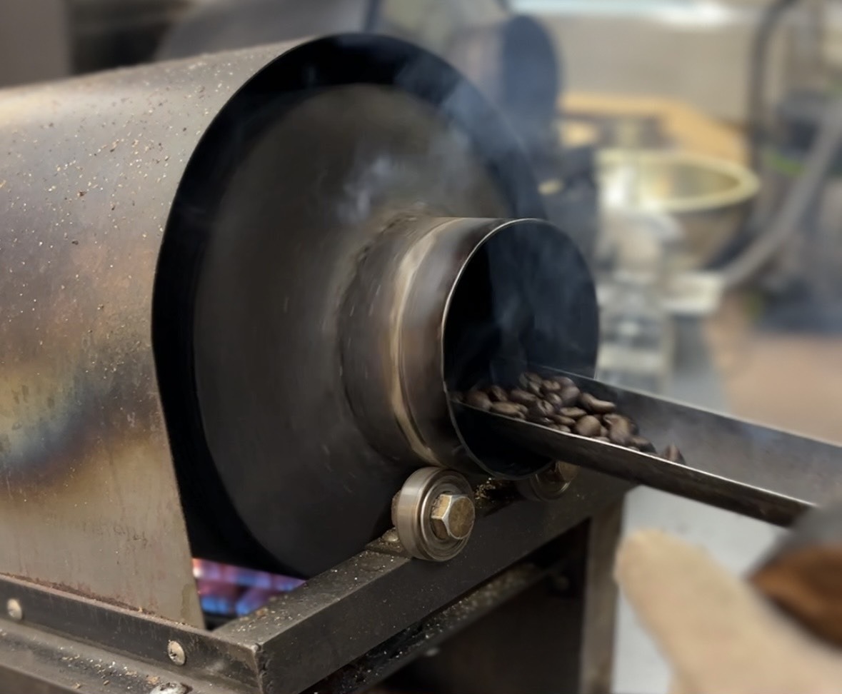 直火の焙煎機から、焼き上がったコーヒー豆を取り出しているところ
